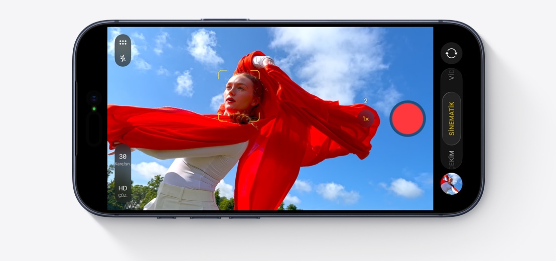 iPhone ekranında, dalgalanan kırmızı atkısıyla dışarıda dans eden bir kişiyi çeken Sinematik Mod gösteriliyor